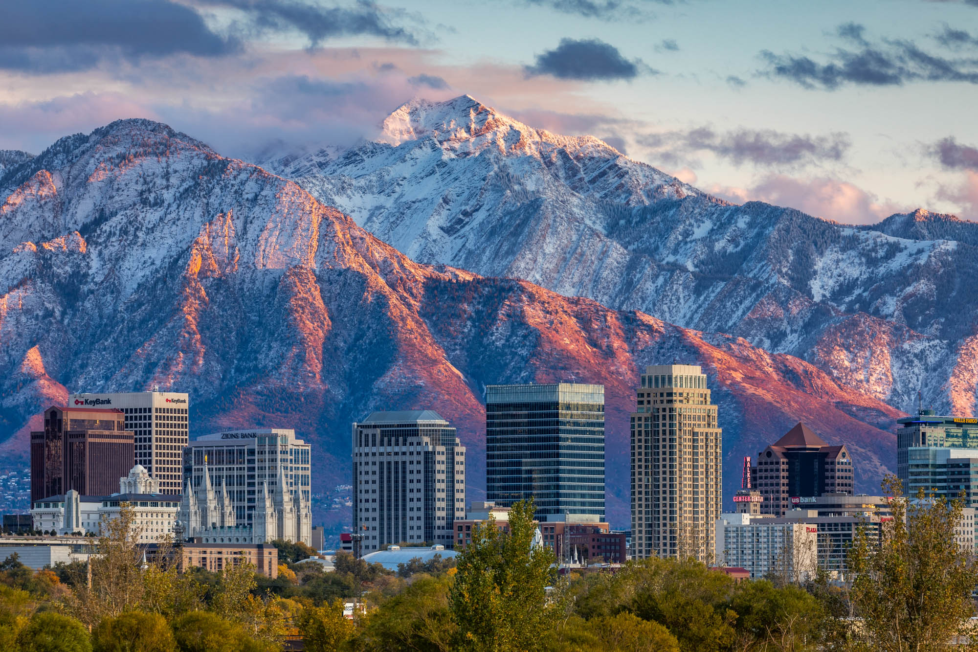 Salt Lake City skyline beneath snow-covered mountains at sunset